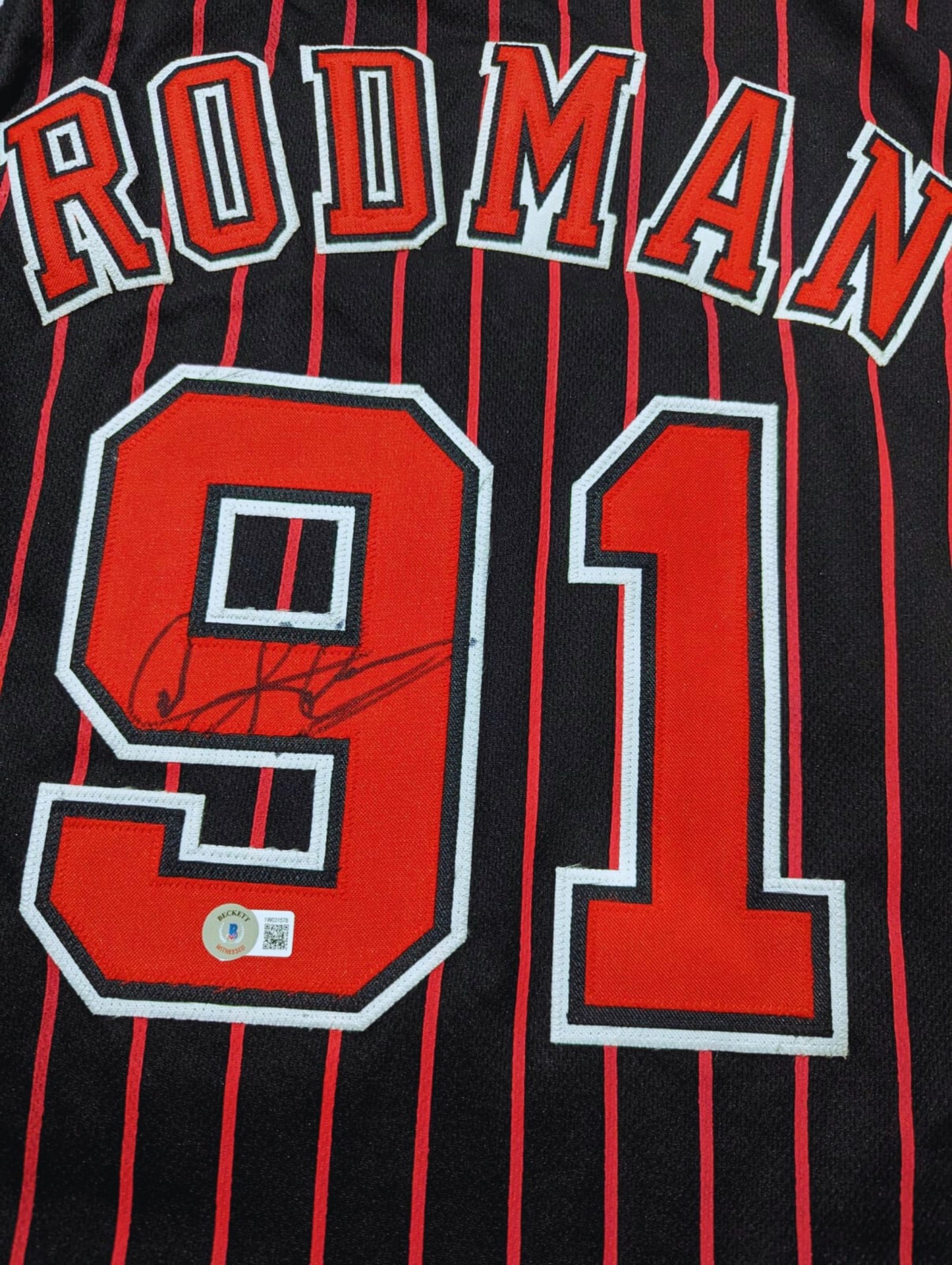 Playera autografiada por Dennis Rodman firma autentificada por la compañía Beckett con el número 1W031578.