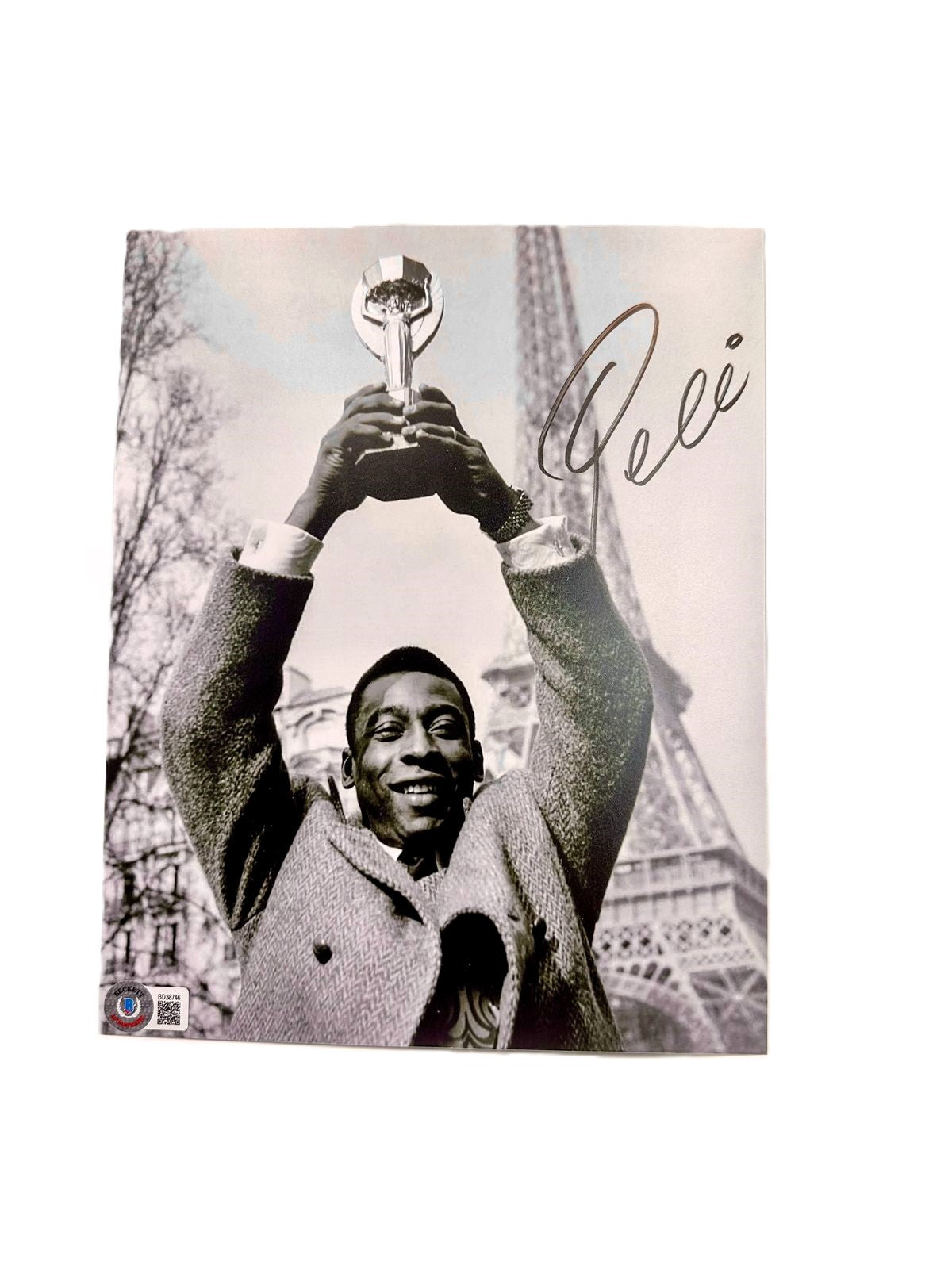 Pele Fotografía autografiada “Copa en París”, firma certificada por la compañía Beckett con el número BD38746.