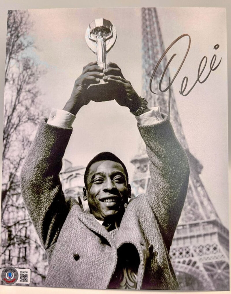 Pele Fotografía autografiada “Copa en París”, firma certificada por la compañía Beckett con el número BD38746.